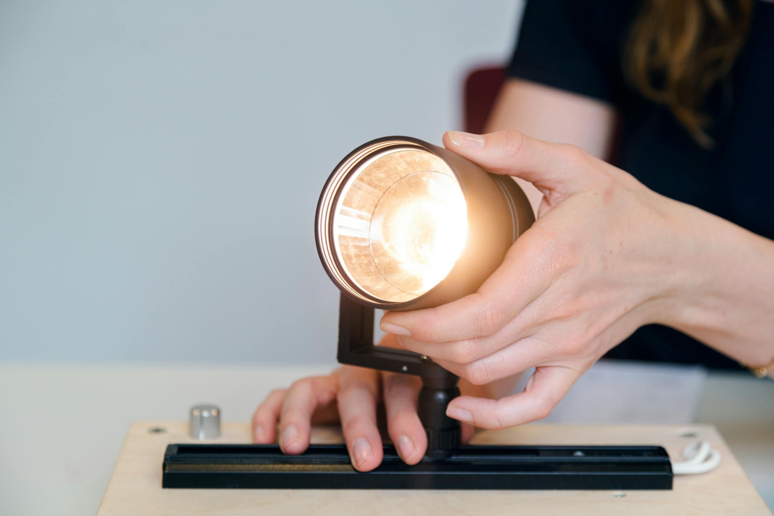 A female engineer testing a light fixture prototype in an office setting, showcasing innovation.
