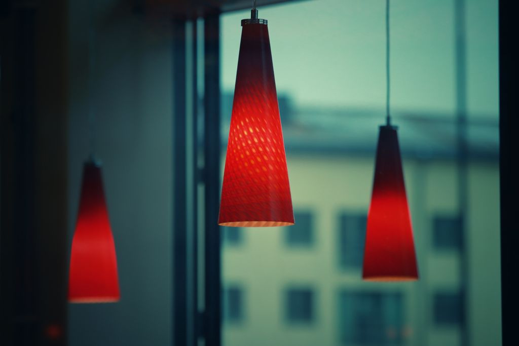 Three red pendant lamps casting a warm glow in a cozy, elegant interior setting.